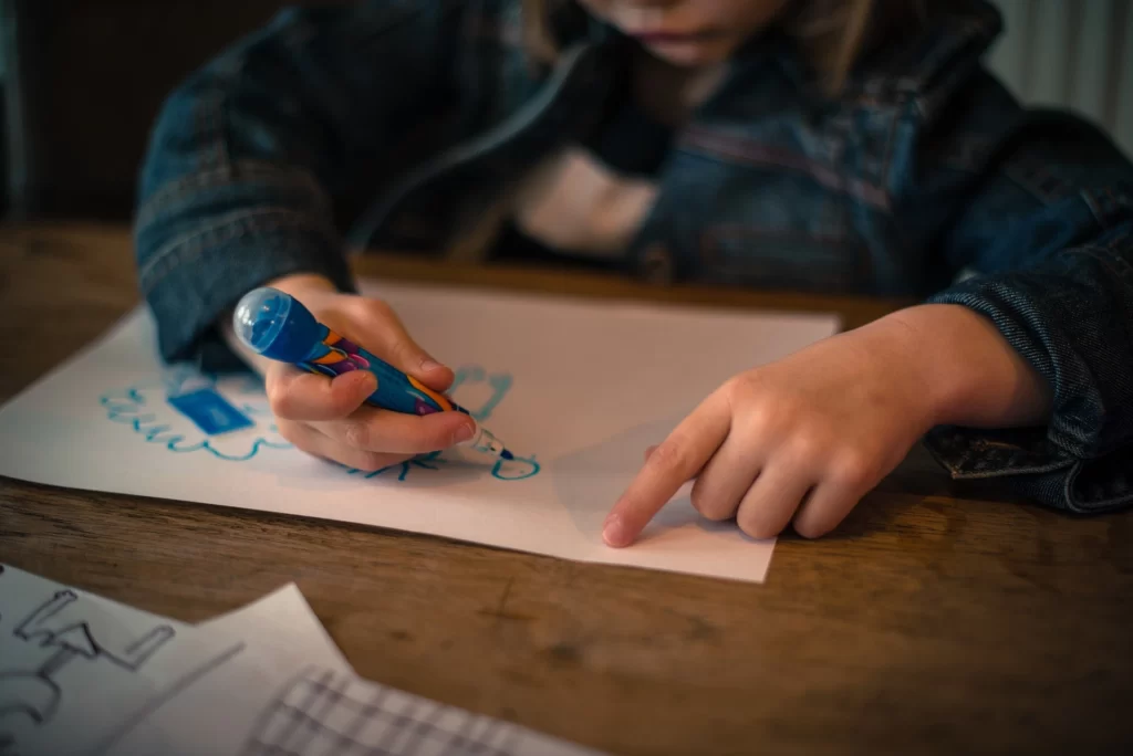 Un copil ce deseneaza pe o foaie de hartie
