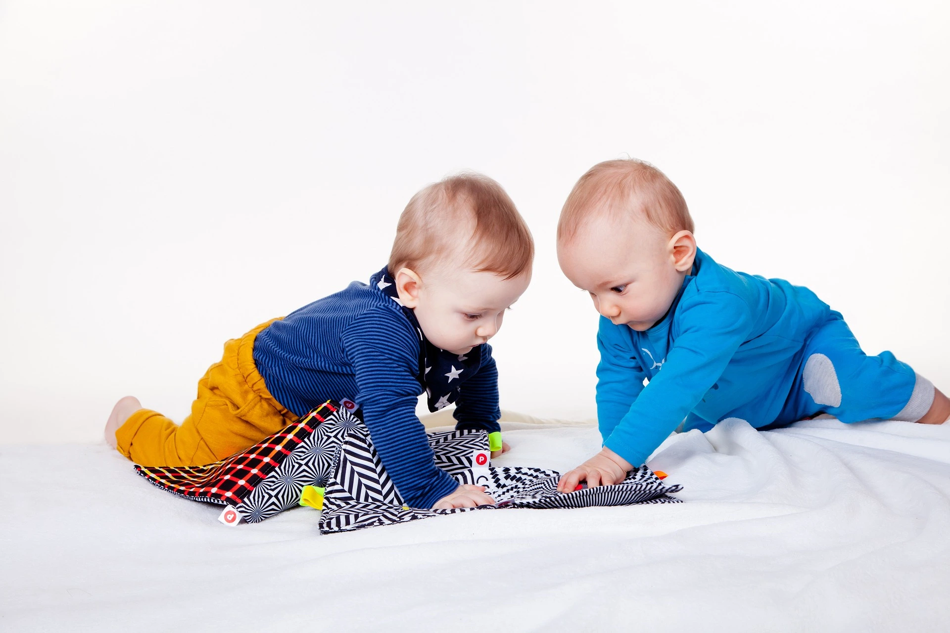 Doi copii se joaca împreună cu o pătură senzorială.